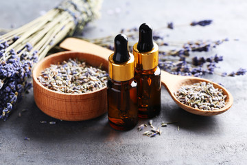 Lavender oil and flowers on grey table