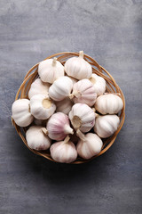 Garlic in basket on grey wooden table