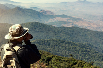 travel hiker man is using binoculars to looking nature on mountain