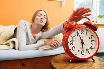 Woman waking up turning off alarm clock in morning