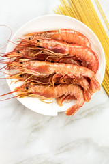 Raw shrimps with pasta, and copyspace on white table