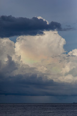 Rainbow clouds seascape. Beautiful colored sky. Unusual ocean weather.