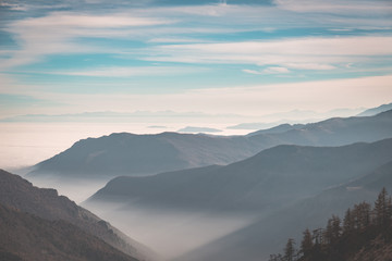 Obraz premium Distant mountain range with fog and mist covering the valleys below.Italian Alps, toned image.