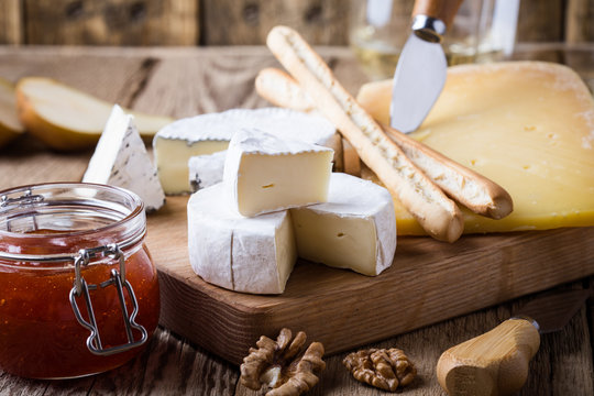 Cheese platter with wine, jam and walnuts on wooden board