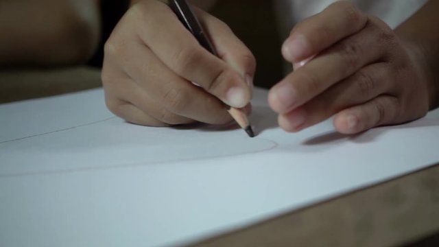 Little asian girl writing on desk in dark room, slow motion shot.
