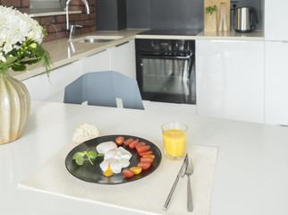 Breakfast with poached eggs and tomatoes on kitchen table