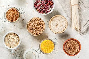 Selection of gluten-free products, cereals: xanthan gum. buckwheat,Rice, rice noodles, chickpeas, lentils, corn, beans, oatmeal. In bowls and jars, the top view on white table top view copy space