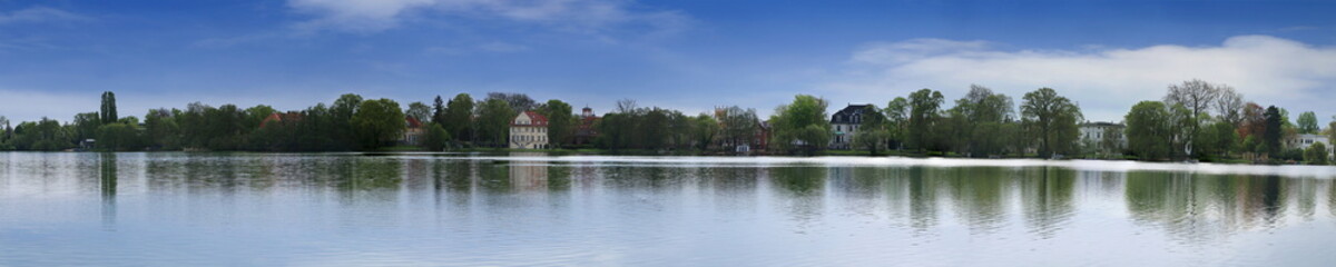 Panorama of a countryside landscape in clear weather with a large lake, trees and houses. Panorama of the Heiliger lake in Potsdam, Germany.