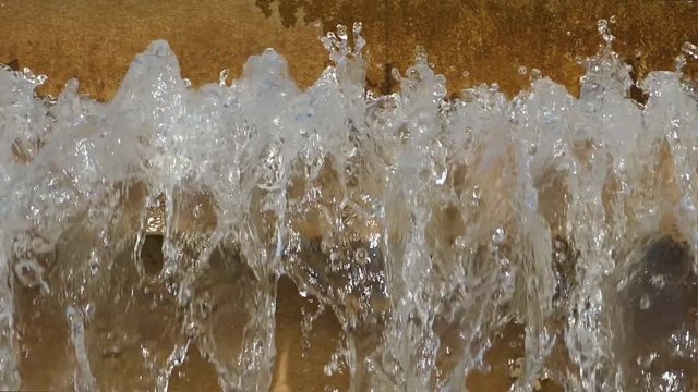 Detail of continuous movement of water falling into a fountain, creating a water curtain. Slow Motion.