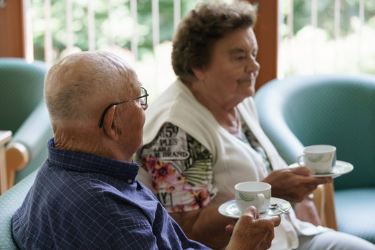 Senior couple having cup of coffee while chatting in nursing home