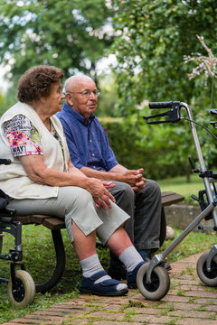 Senior man and woman in retirement home sitting on a bench in park