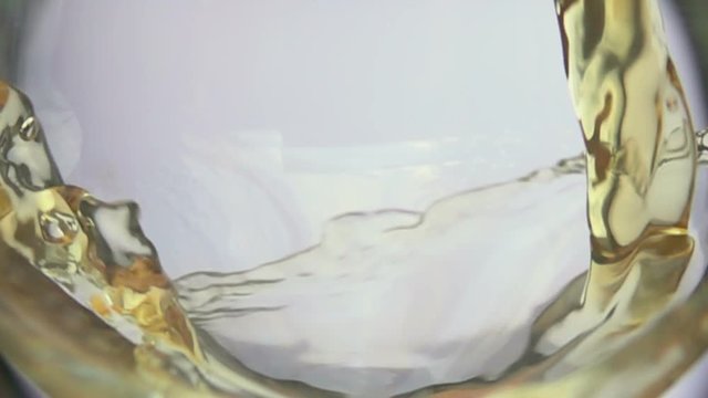 Wave of white wine curls in a glass