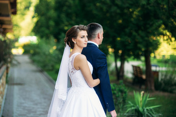 Beautiful couple walking in the park in their wedding day. Sunny weather.