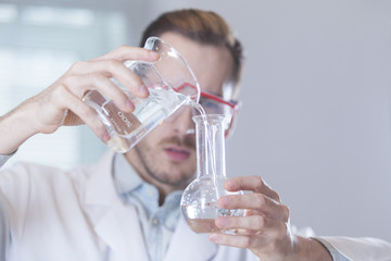 scientist pouring liquid into beaker