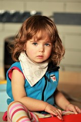 Portrait of a cute one year old girl sitting and looking straight into the eyes