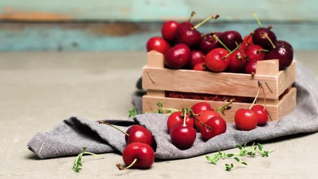 Red ripe cherries in small wooden box on kitchen countertop. Slide from left.