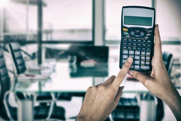 Composite image of hands of businesswoman using calculator