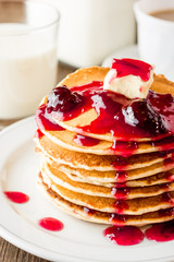 Pancakes with butter and jam on wooden table.