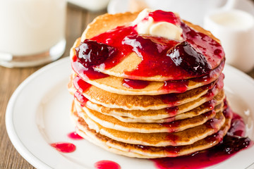 Pancakes with butter and jam on wooden table.