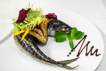Sea fish, dressed with vegetables and olives on a white plate. Sea fish, dressed with vegetables and olives on a white plate. Horizontal frame