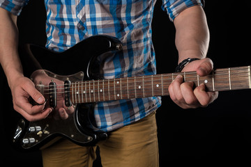 Music and art. Electric guitar in the hands of a guitarist, on a black isolated background. Playing guitar. Horizontal frame