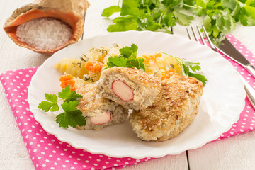 Fish cutlets stuffed with surimi and stewed potatoes with carrots