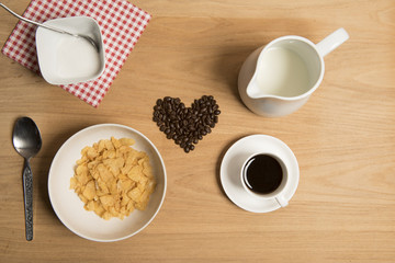 Bowl of cereal with coffee, coffee beans, milk and sugar. 