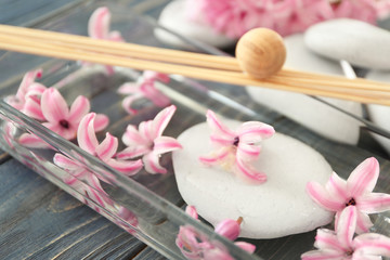 Beautiful spa composition with flowers in glass tray on table