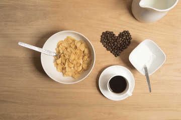 Bowl of cereal with coffee, coffee beans, milk and sugar. 