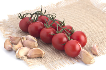 Cherry tomatoes and garlic on a canvas napkin on a white background