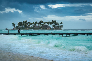 A man walks along a jetty on a stormy day in the Maldives