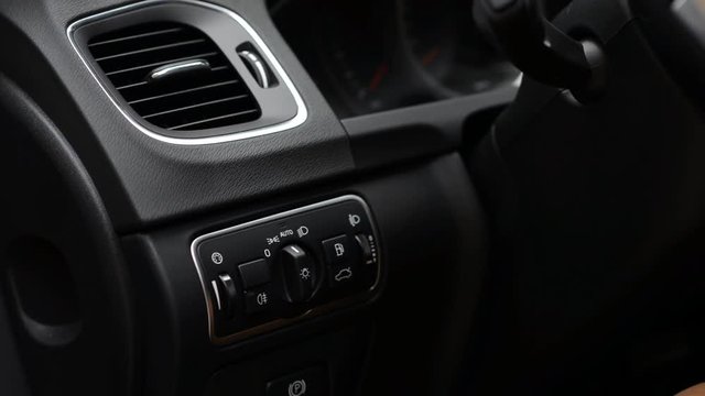 Man changing modes of headlights in car, switching to off, auto and beam lights