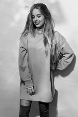 Young pretty cute woman with long straighthair in gray sweatshirt, grid pantyhose and hessian boots.