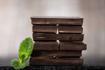 Stack of chocolate slices with mint leaf. dark chocolate over wooden background, selective focus