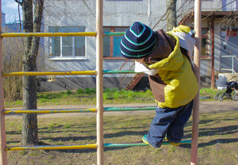 Fototapeta na wymiar little boy, in kindergarten, on the Playground, climbs on the Swedish ladder. The child climbs on the Playground..