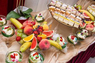 Wedding catering fruits and cakes decorative table.