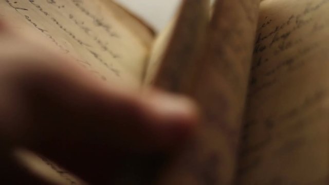 Close up of hands turning pages in a vintage book.