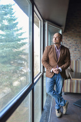 Handsome indian businessman, standing near panoramic window, full length shot