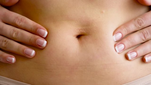 Woman standing and grabbing her tummy with her hands