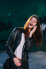 Young beautiful brunette walk in a city talking to her  mobile phone against a grundge background and a strong backlight