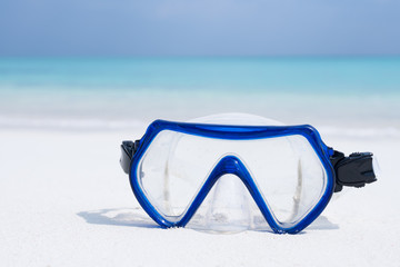 Swimming mask on white sandy seashore