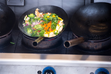 Cut vegetables stewed in a pan on a large industrial stove