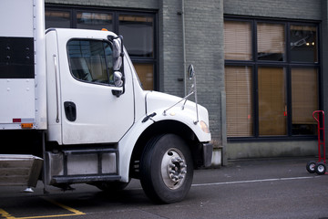 Delivery semi truck with box body standing on street of urban city