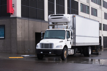 Fototapeta premium Small semi truck with reefer unit on box trailer for local delivery unloading delivered food
