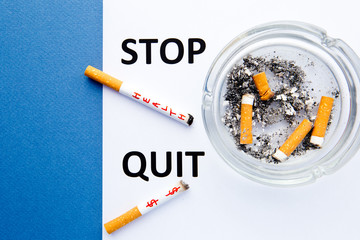 Stop Smoking - Stop and Quit - with cigarettes and ashtray with printed words on blue and white...