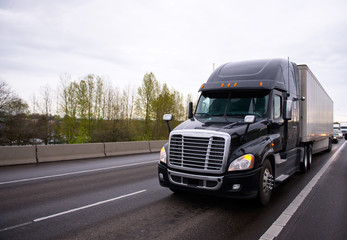 Fototapeta na wymiar Big black modern semi truck rig trailer in traffic on highway
