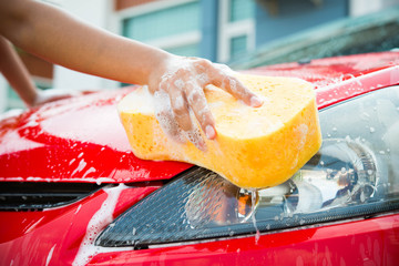  hand with yellow sponge washing car