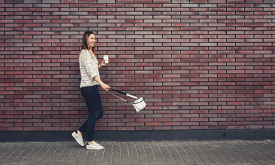 Trendy Girl Walking At The Brick Wall Background With Coffee