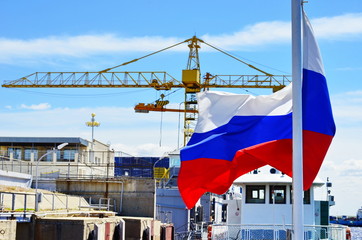 Obraz na płótnie Canvas Waving Russian flag on the background of the port and the crane