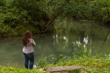 Woman standing and looking at a creek